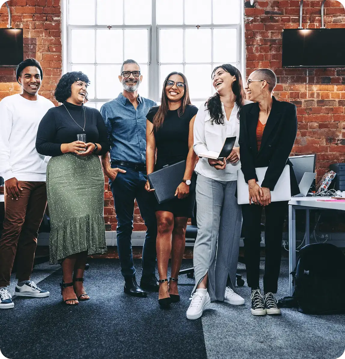 Group of colleagues laughing in office setting.